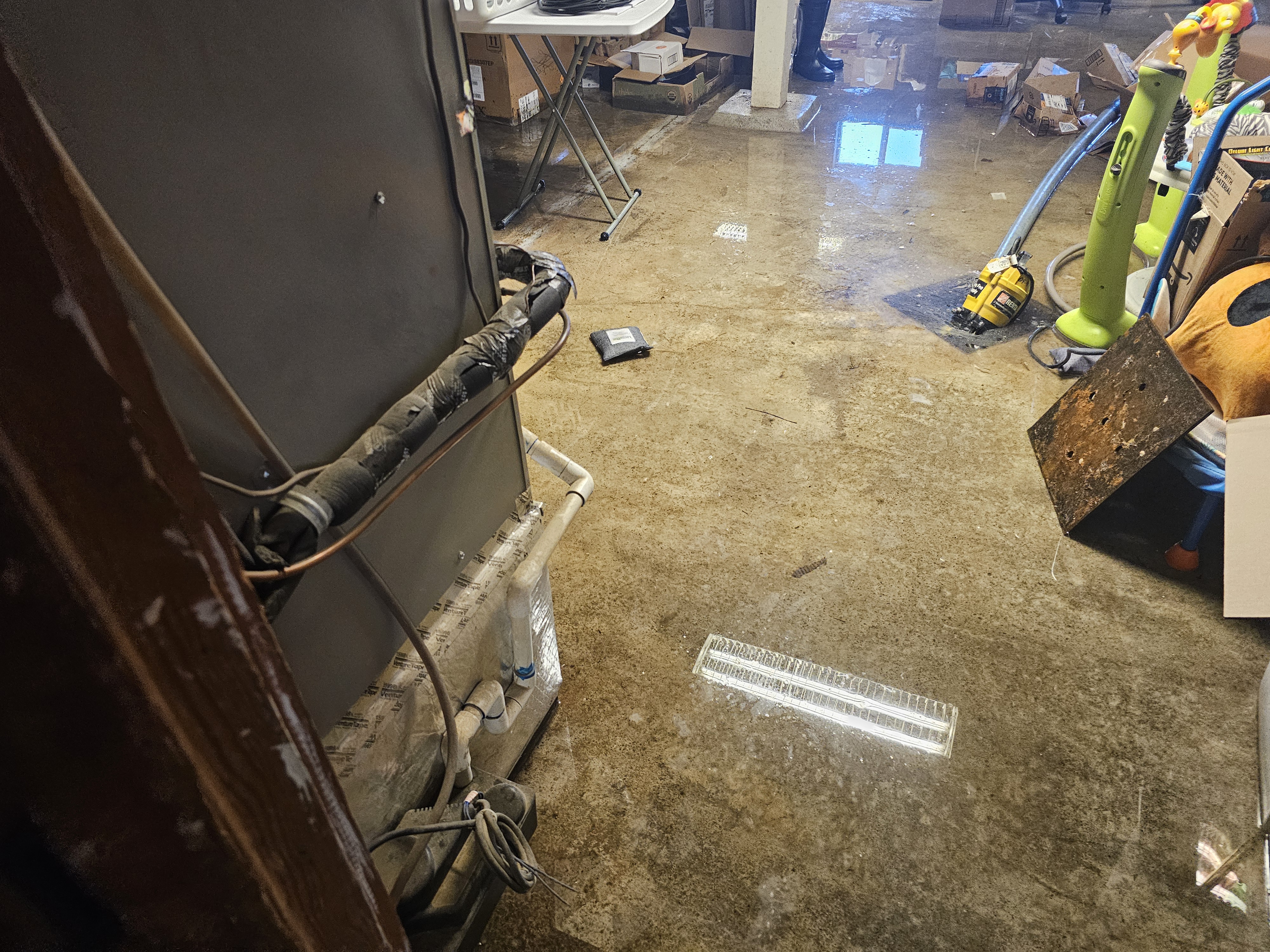 Flooded basement with standing water on concrete floor from burst pipe requiring emergency water extraction