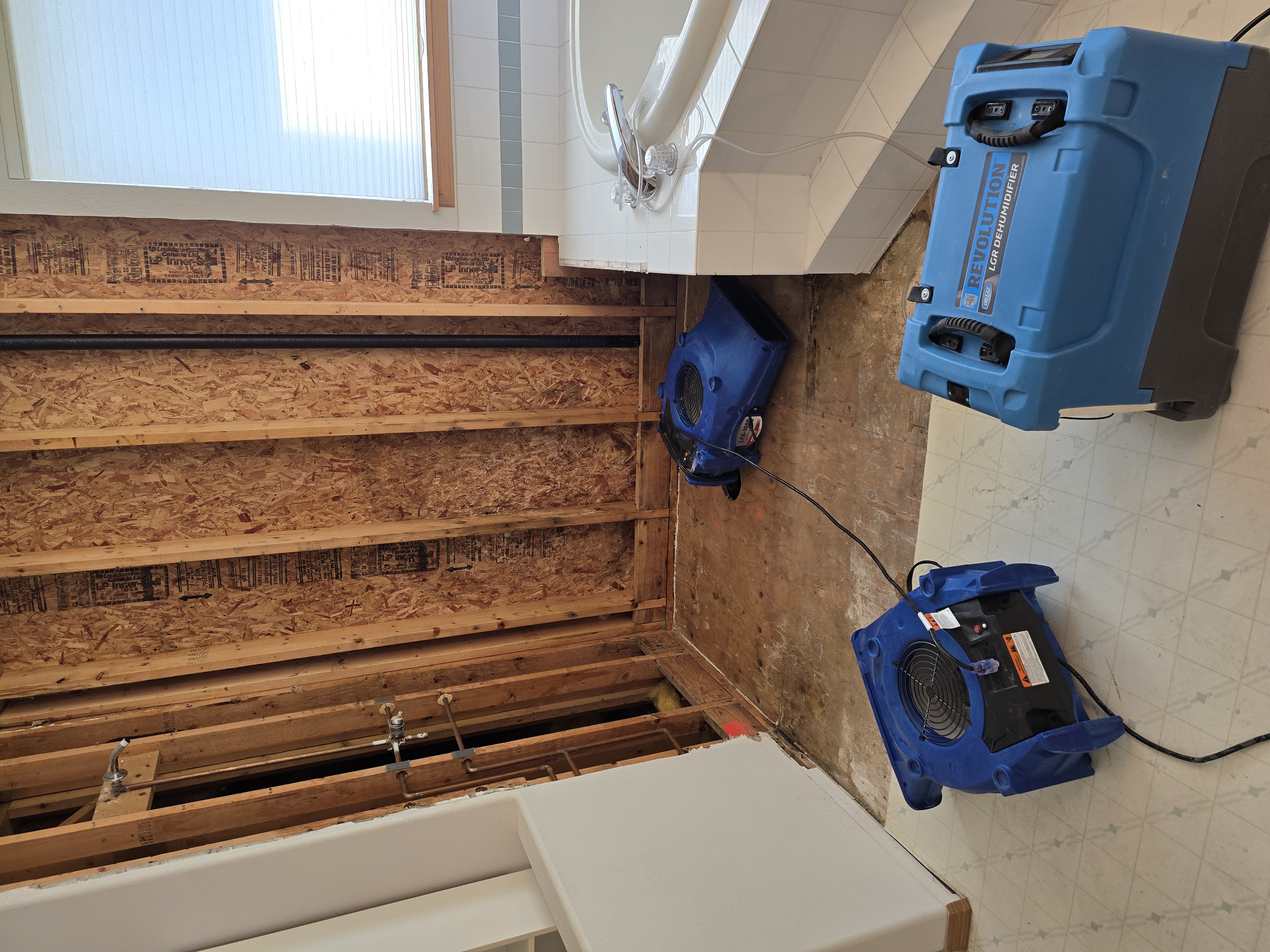 Professional dehumidifier and air mover equipment drying bathroom after water damage restoration