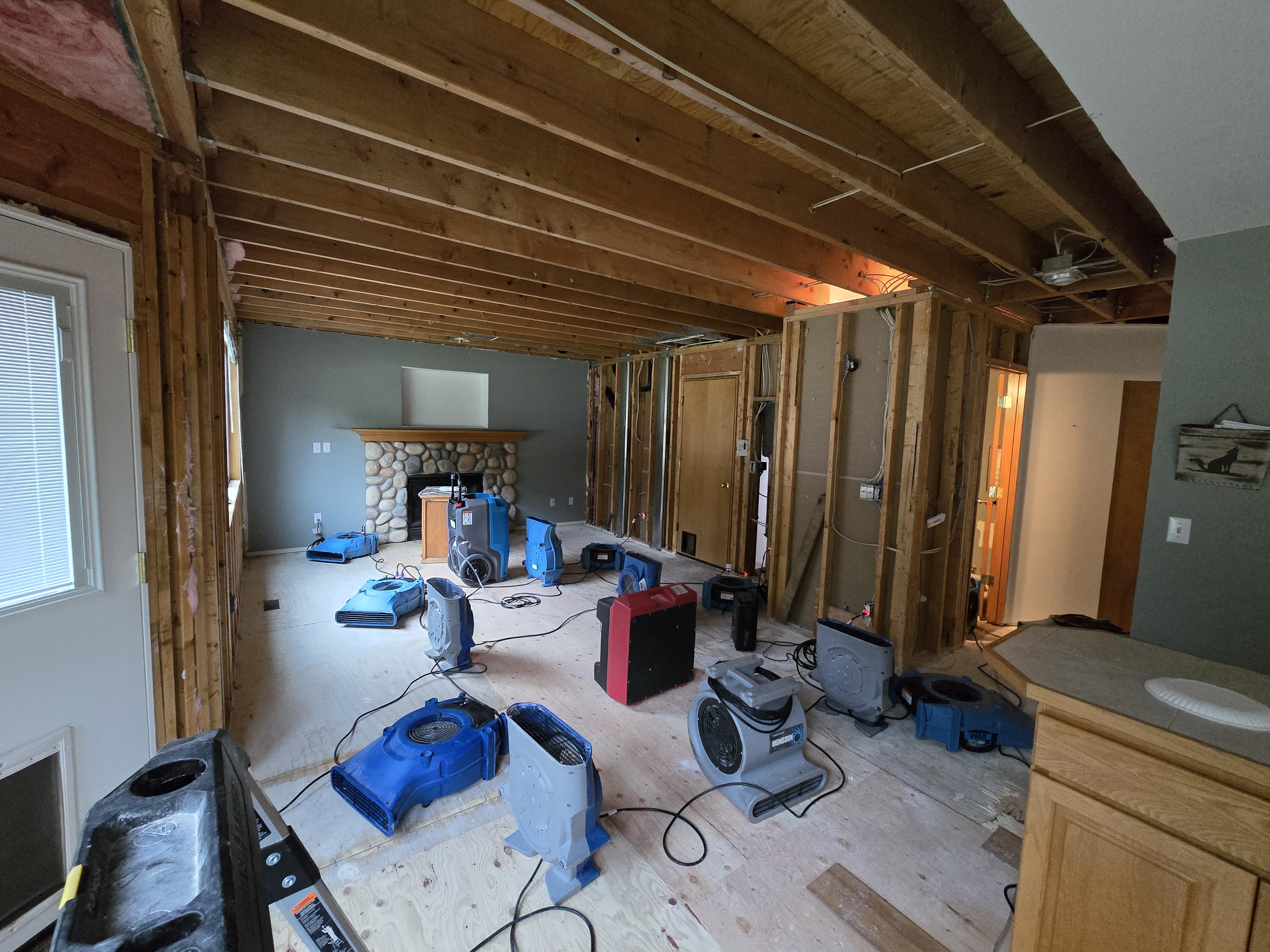 Living room with ceiling drywall and wall removed after water damage requiring structural drying