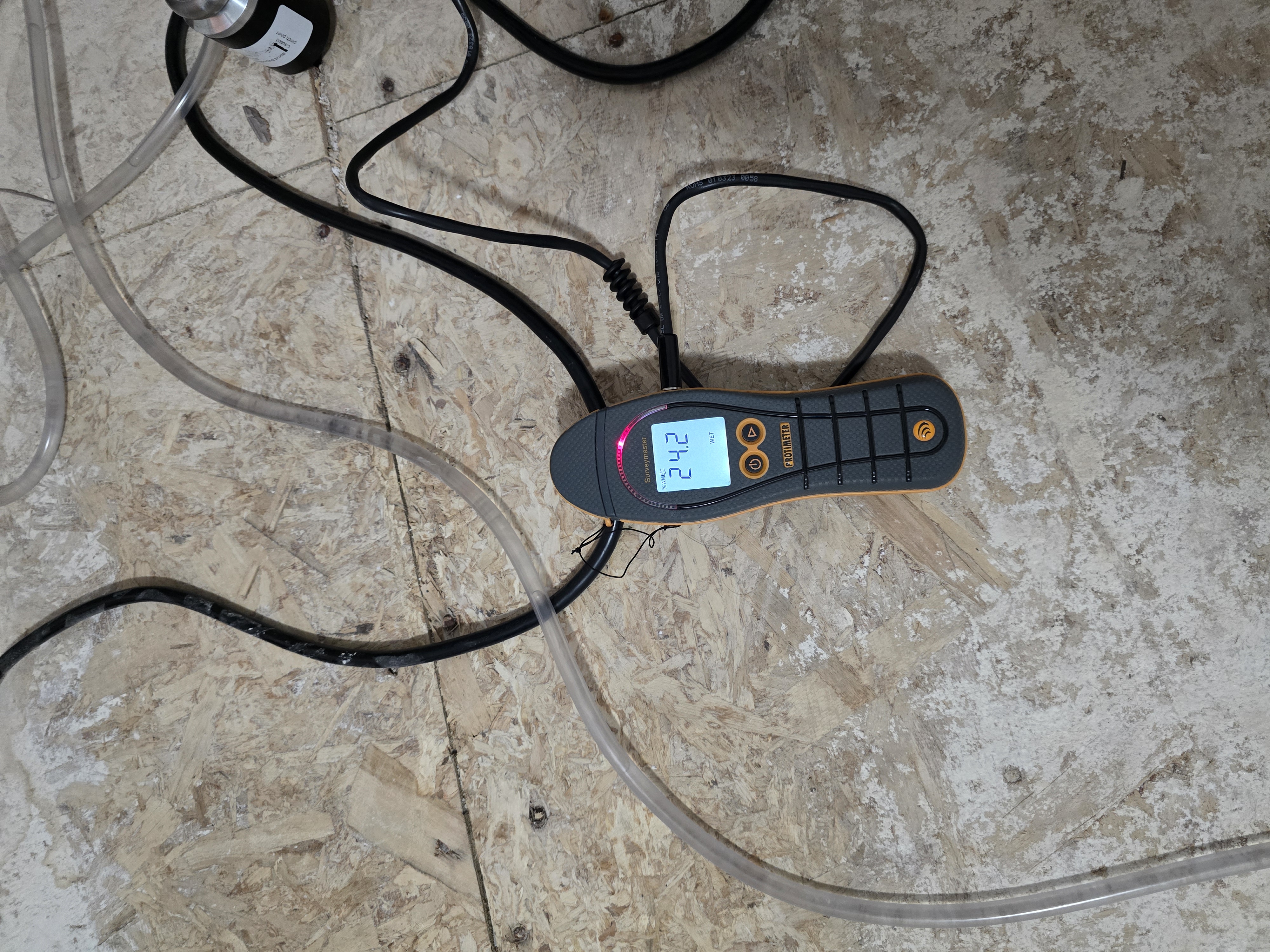 Protimeter moisture meter showing 47.1% reading on water damaged subfloor joists during inspection